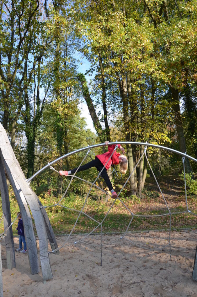 Ein Mädchen klettert auf dem Spielplatz im Schlosspark Weitmar.